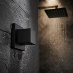 Acabamento quadrado preto para registro instalado em parede de ardósia com chuveiro ligado ao fundo