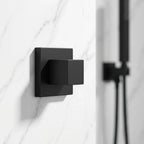 Acabamento quadrado preto para registro instalado em parede de mármore branco em banheiro moderno