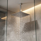 Chuveiro de teto quadrado cromado instalado em box de porcelanato com chuva ampla