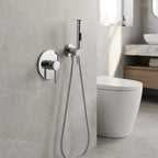 Ducha higiênica Royal Orion cromada instalada em parede de porcelanato cinza ao lado do vaso sanitário