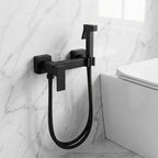 Ducha higiênica Royal Square preta instalada em parede de mármore claro ao lado do vaso sanitário
