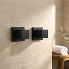 Kit com dois acabamentos quadrados preto fosco para registro instalados em parede de porcelanato travertino bege em banheiro moderno