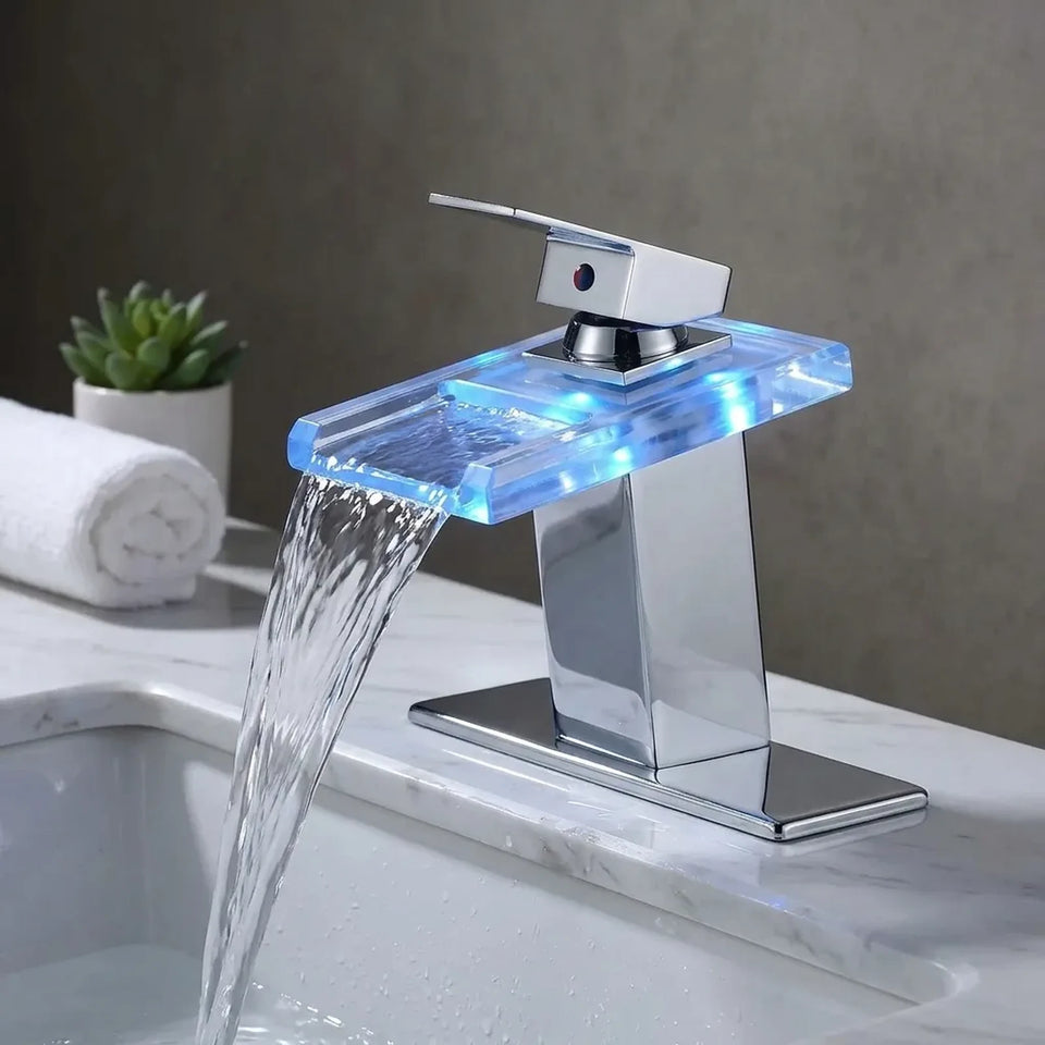 Torneira AquaGlam cromada com placa para 3 furos ambientada em bancada de mármore, cascata com LED azul