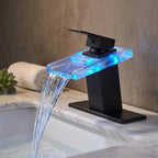 Torneira AquaGlam preta com placa para 3 furos ambientada em bancada de mármore, cascata com LED azul