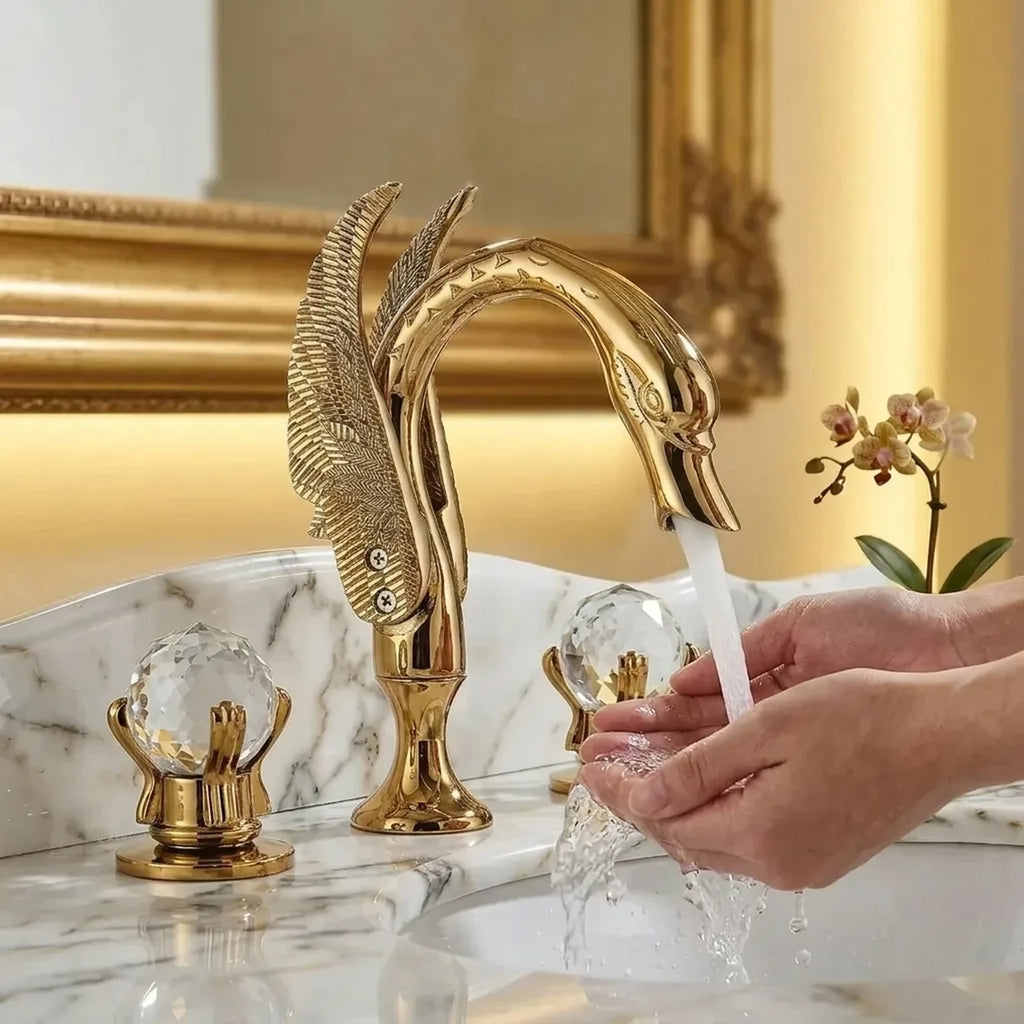 Torneira dourada modelo cisne em uso, mãos sob o jato de água que sai do bico na cuba do lavabo