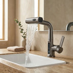 Torneira digital cascata grafite instalada em cuba branca sobre bancada de travertino em banheiro moderno, com jato cascata em funcionamento