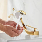 Mãos sendo lavadas sob o jato da torneira gourmet monocomando AquaElite branca com detalhes dourados em cuba de banheiro