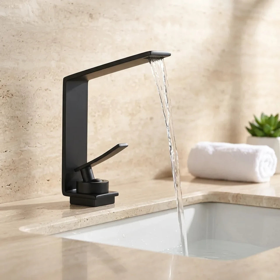 Torneira LuxStream cascata preta instalada em bancada de travertino com cuba de embutir branca