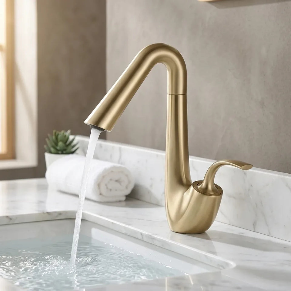 Torneira Platine Dourado Escovado ambientada em banheiro com bancada de mármore branco