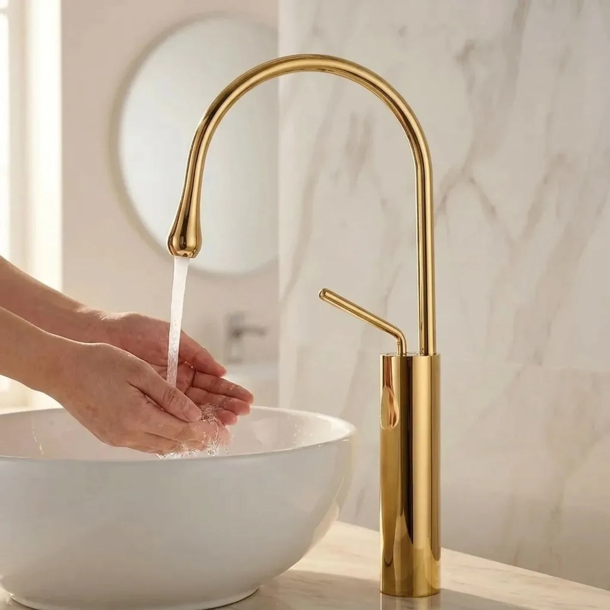 Mãos lavando sob o jato da torneira Prestige dourada, com a água caindo dentro da cuba de apoio branca